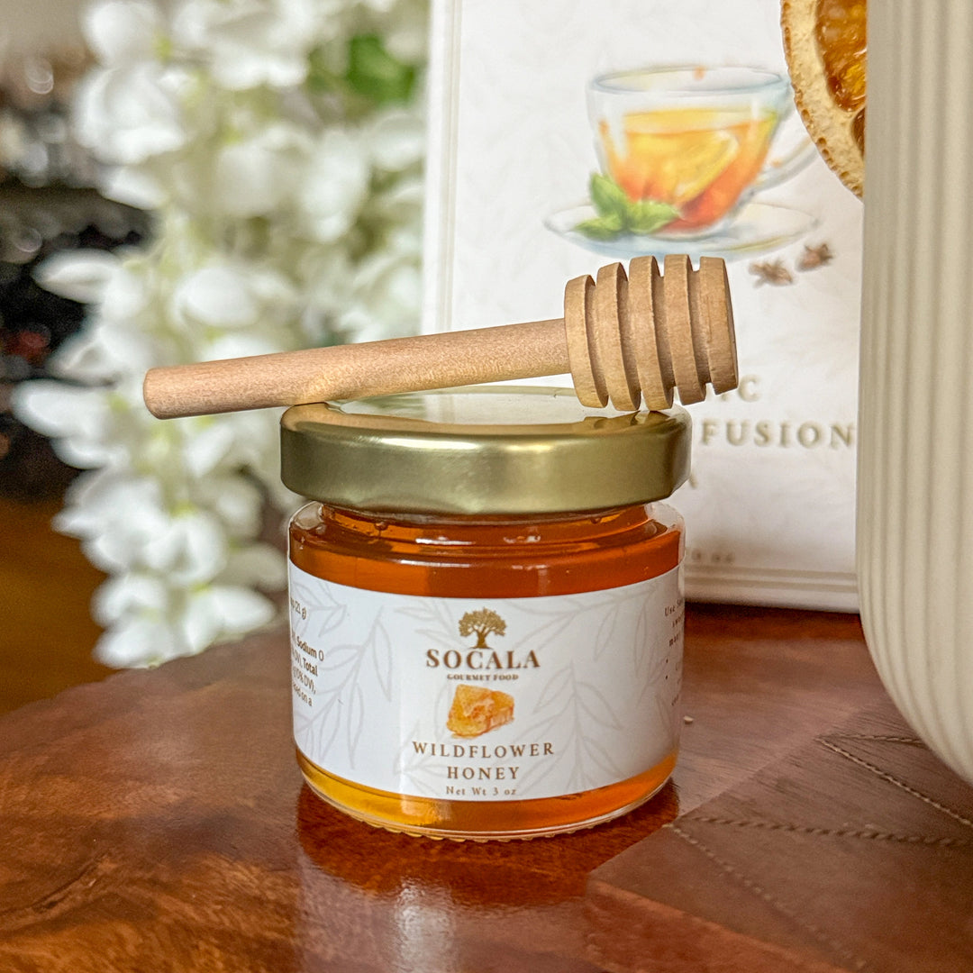 Jar of Socala Wildflower Honey with a wooden dipper on a wooden surface.