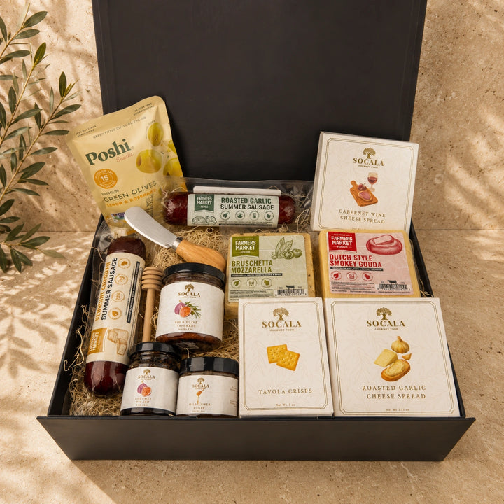 Gourmet food gift box with various items including cheese, honey, and crackers on a beige surface.