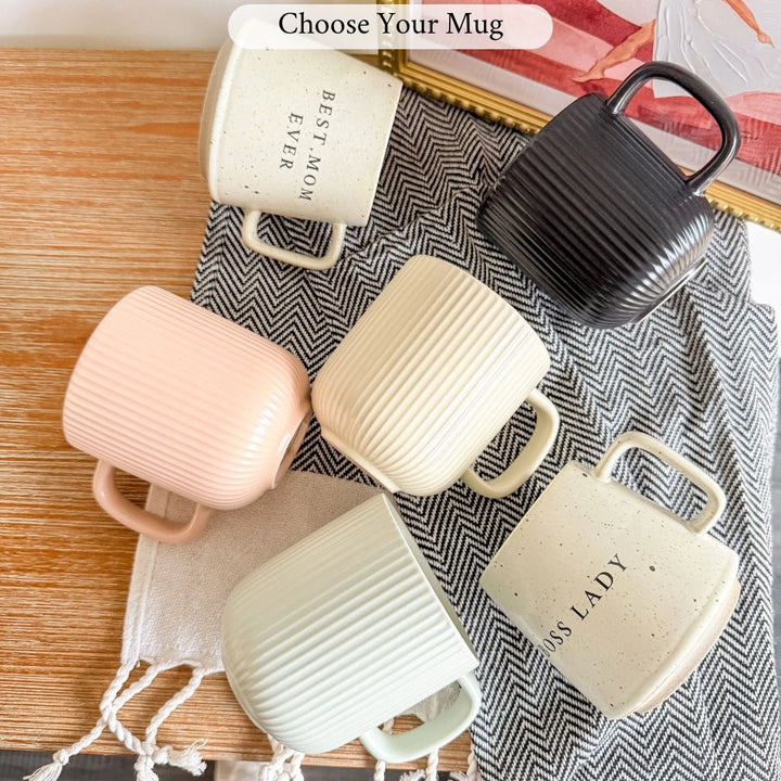 Set of ceramic mugs in various colors on a textured surface with text 'Choose Your Mug'.