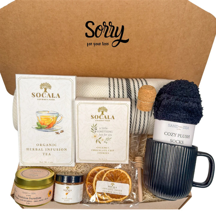 Gift box with blanket, tea, snacks, and a mug labeled &