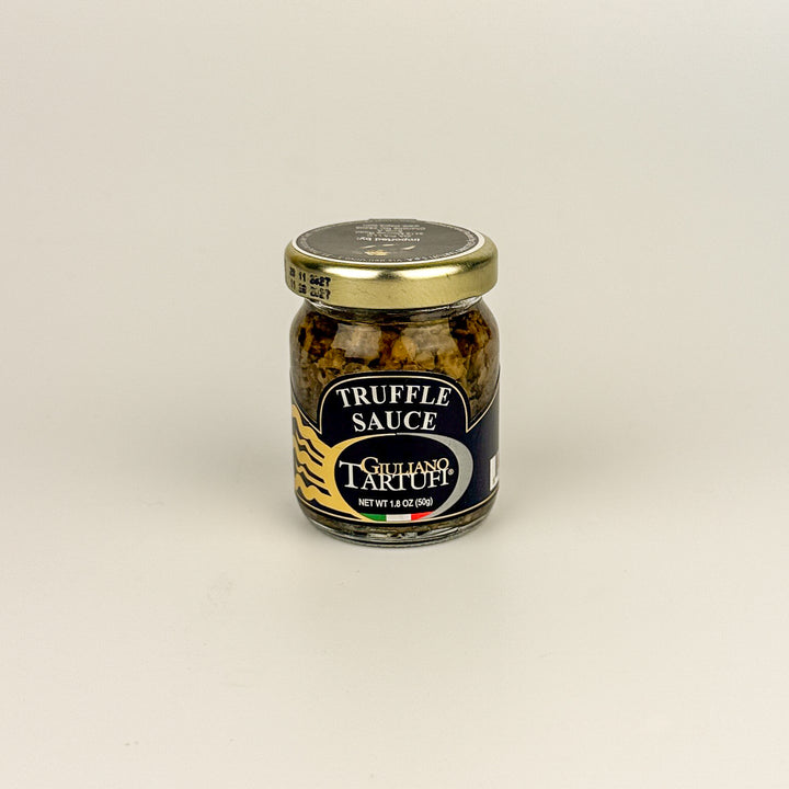 Jar of truffle sauce with a gold lid on a beige background