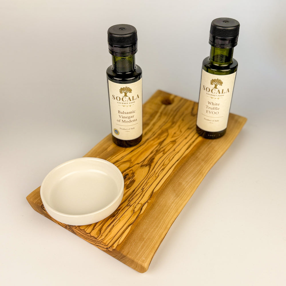 Two bottles of Socala olive oil on a oliive wooden board with a white background
