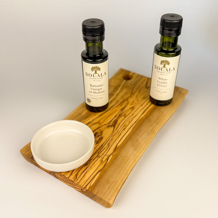 Two bottles of Socala olive oil on a oliive wooden board with a white background