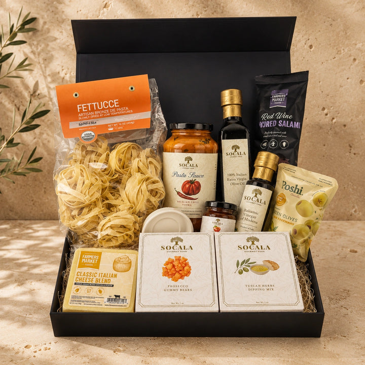 Gourmet food gift box with pasta, sauces, and other Italian products on a neutral background.