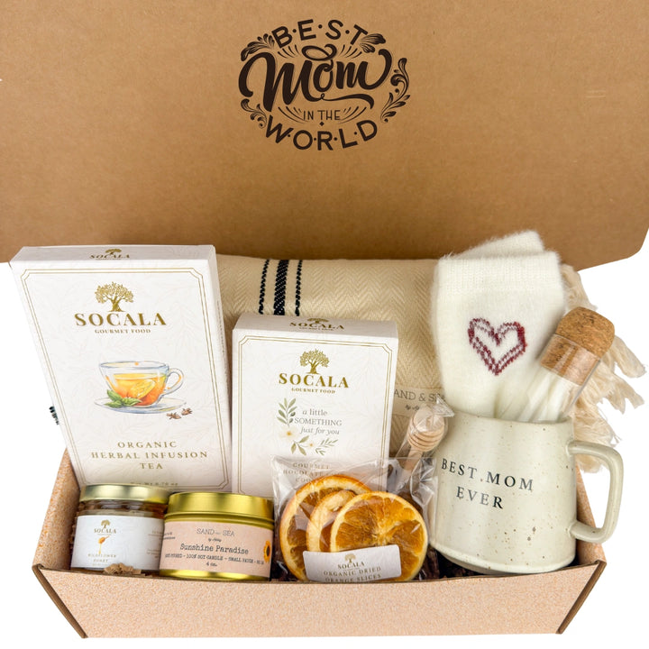 Gift box with tea, candles, and a mug labeled 'Best Mom Ever' on a brown background.