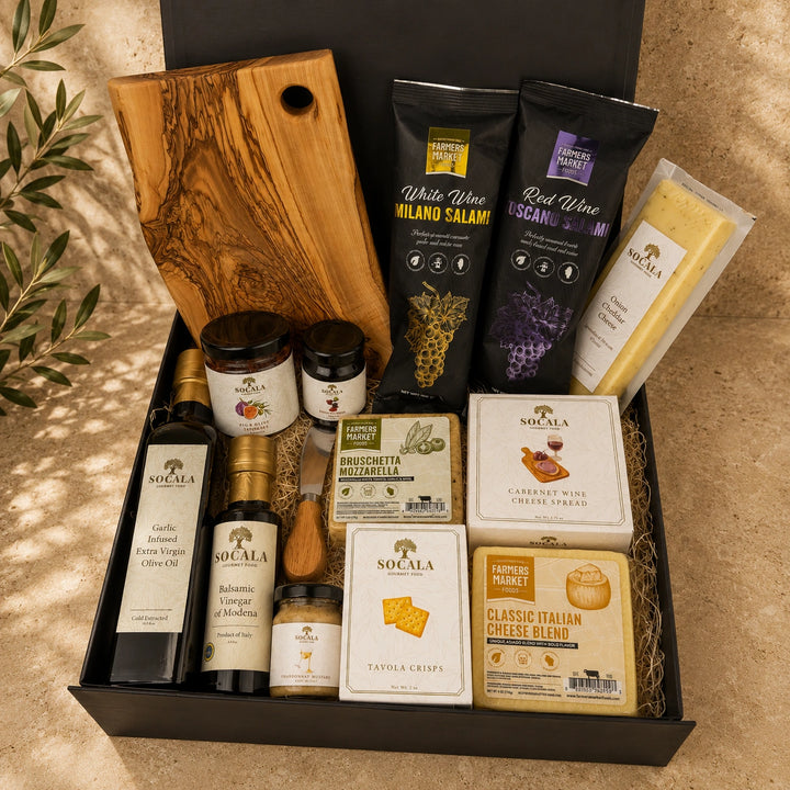 Gourmet gift basket with various food items including cheese, wine, and olive oil on a textured surface.