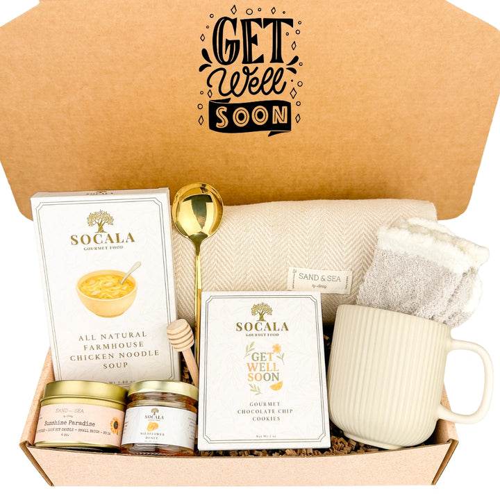 Get well soon care package with a mug, chicken noodle soup, cookies, blanket, and other items in a box.