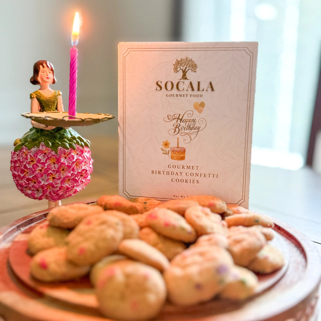 Plate of cookies with a birthday candle and Socala cookie packaging in the background.