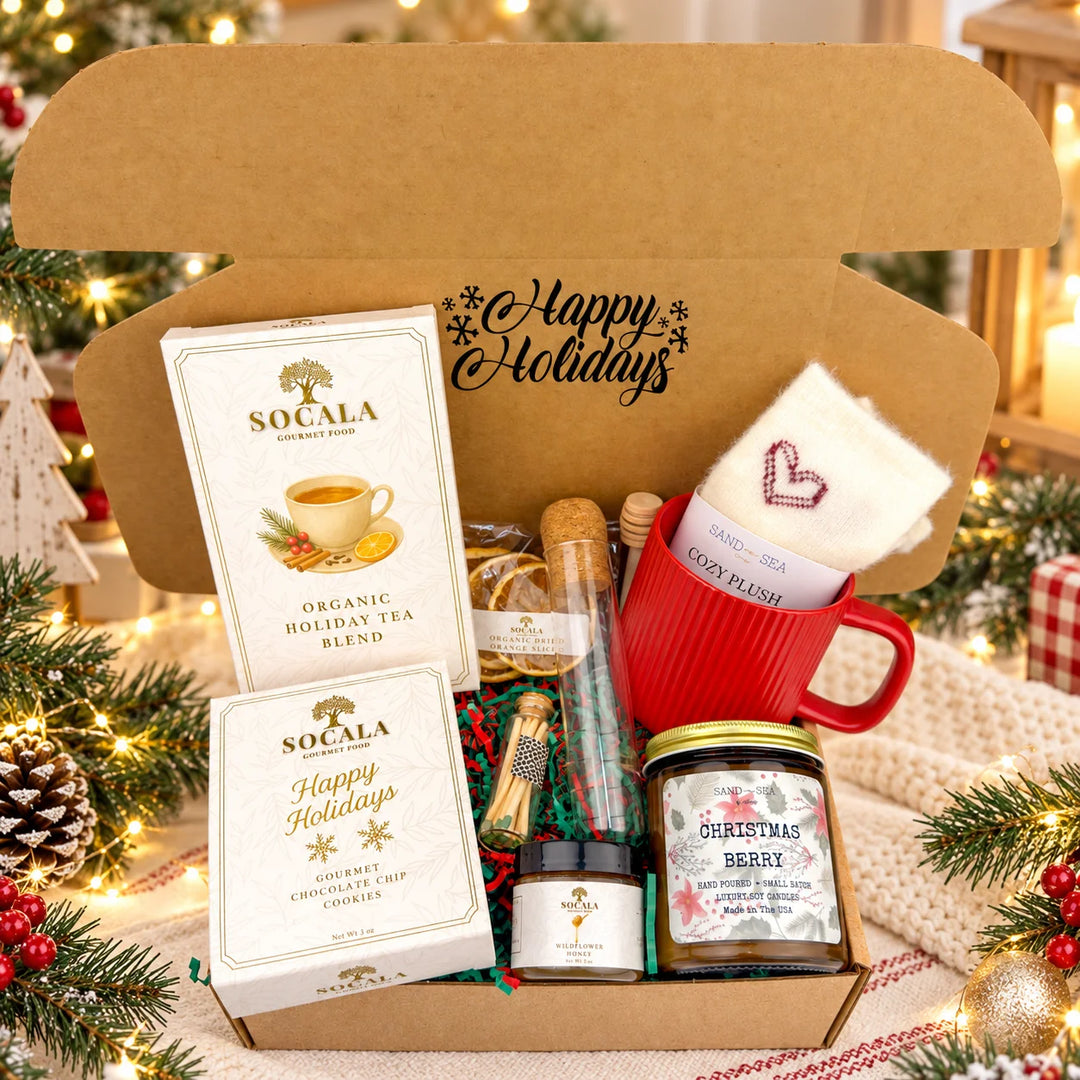 Gift set with Socala tea, cookies, honey, and a candle in a box labeled 'Happy Holidays'.