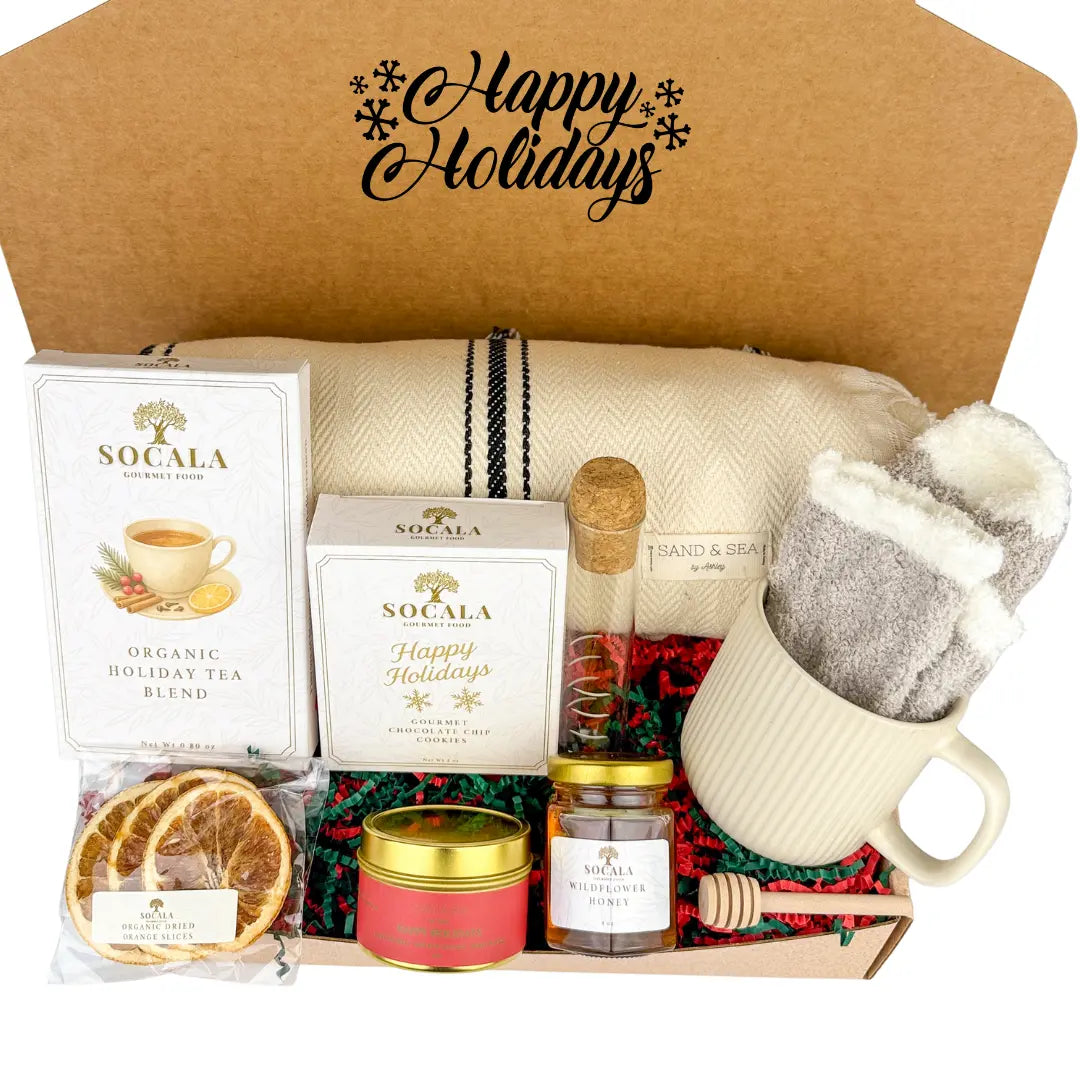 Gift box with holiday-themed items, including a blanket, tea, candles, and a mug.