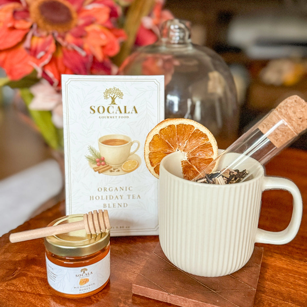 Socala organic holiday tea blend with honey mug and dried oranges on a table.