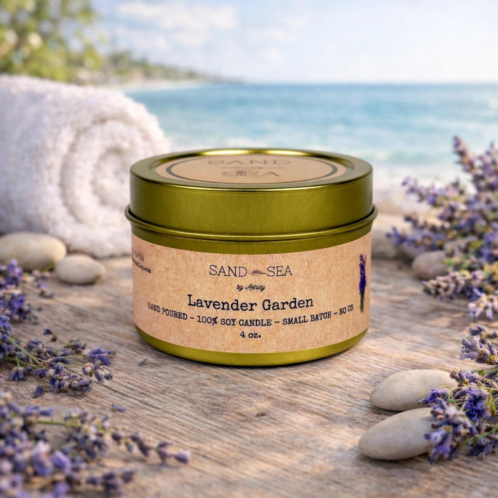 Candle labeled 'Lavender Garden' by Sand Sea on a wooden surface with lavender flowers and stones, blurred ocean background.
