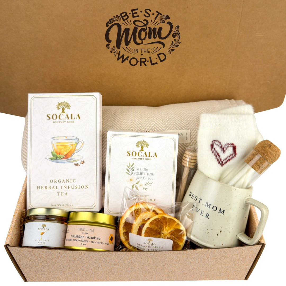 Gift box with tea, snacks, and a mug labeled 'Best Mom Ever' on a brown background.