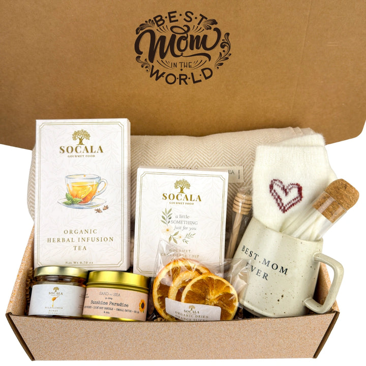 Gift box with tea, snacks, and a mug labeled 'Best Mom Ever' on a brown background.