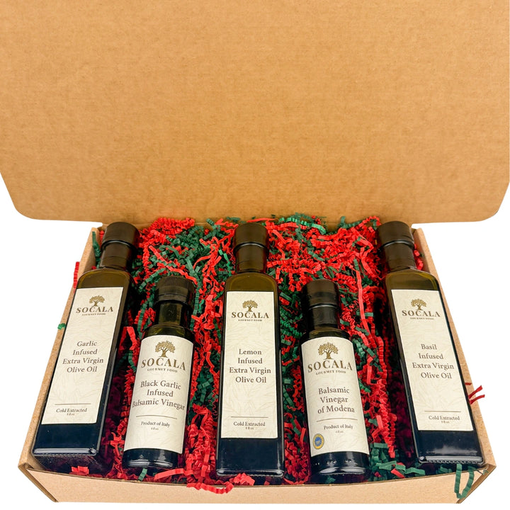 Set of Socala olive oil and vinegar bottles in a gift box with red and green crinkle paper.