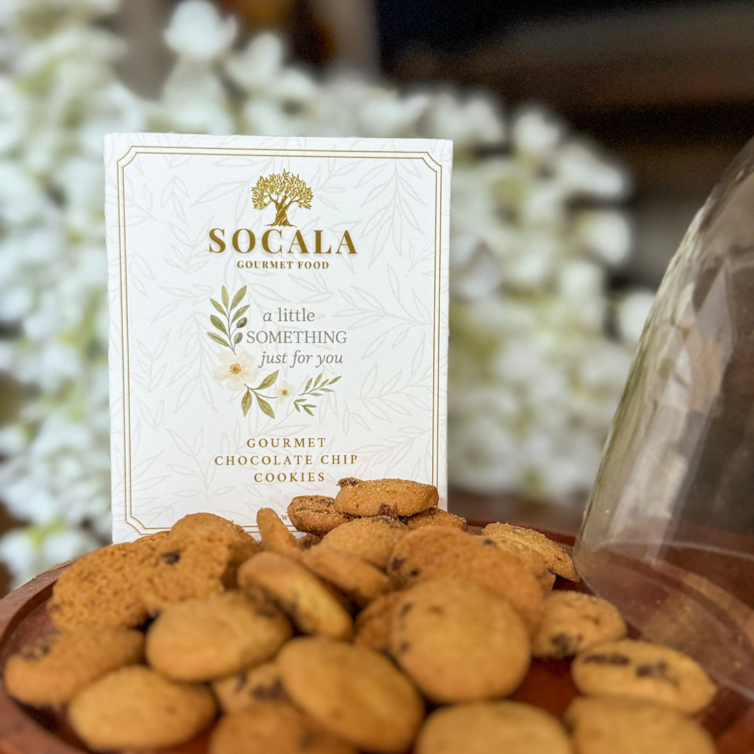 Socala gourmet chocolate chip cookies with a branded card on a blurred floral background