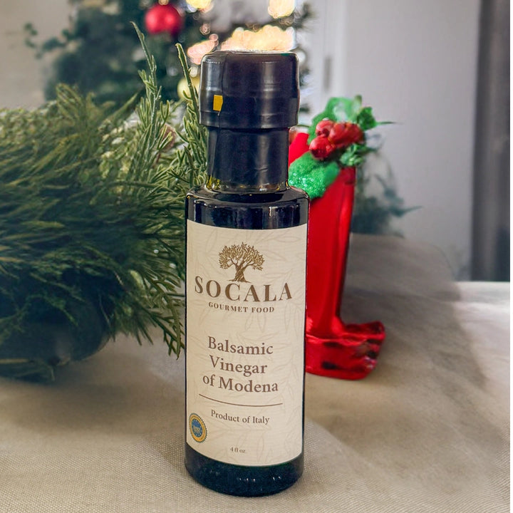 Socala Balsamic Vinegar of Modena bottle on a table with decorative items in the background