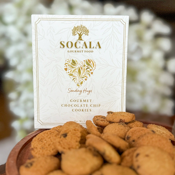 Socala gourmet chocolate chip cookies with a decorative box on a blurred floral background