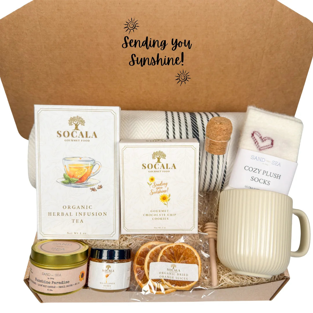 Gift box with luxury blanket tea packaging, a mug, and other items with 'Sending you Sunshine!' text on a brown background.