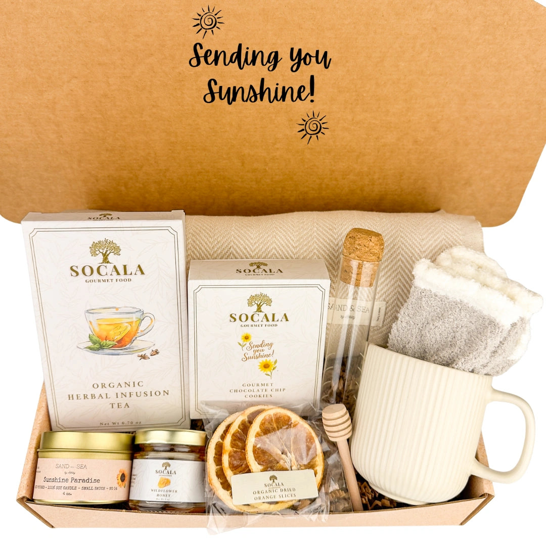 Gift box with luxury blanket tea packaging, a mug, and other items with 'Sending you Sunshine!' text on a brown background.