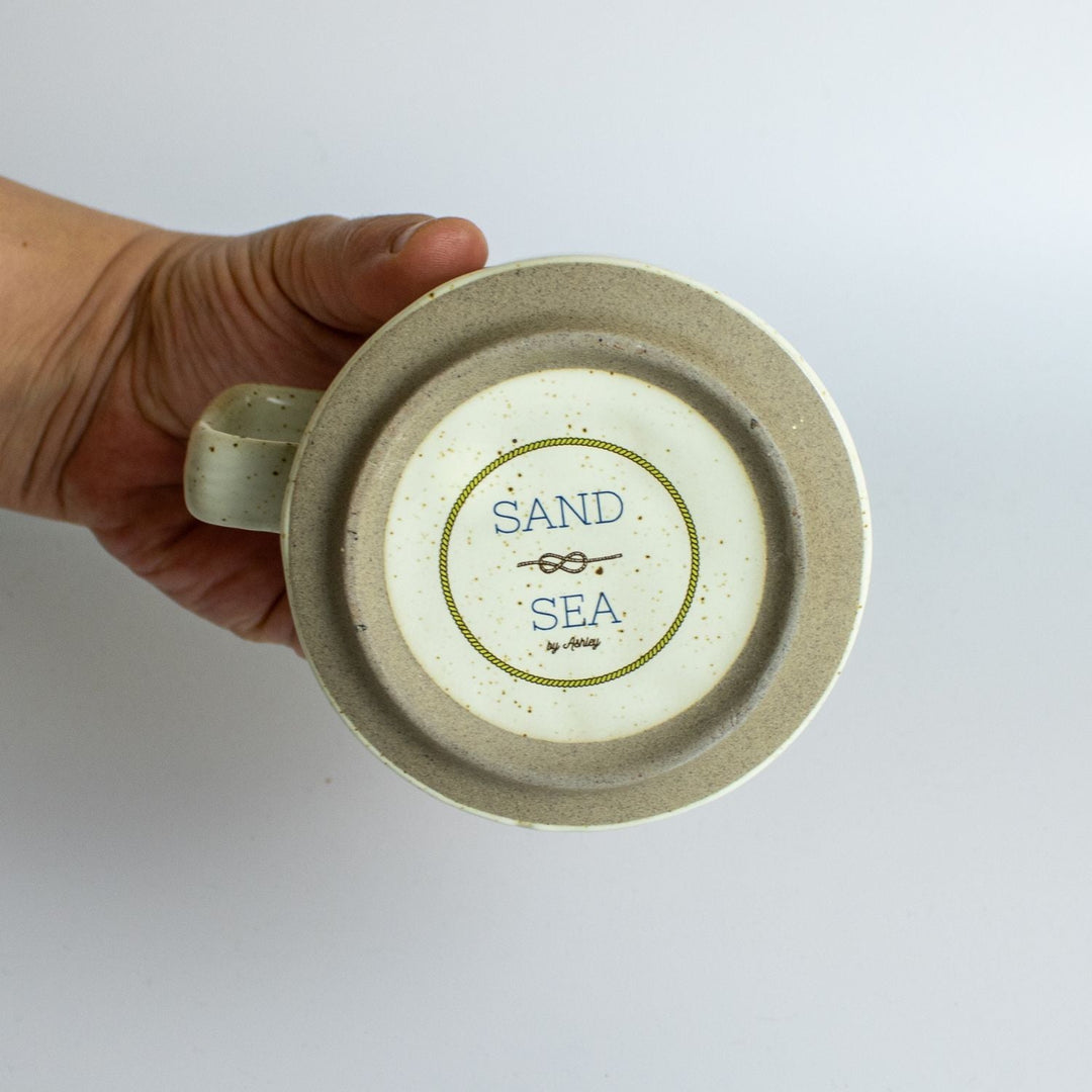 stoneware-mug-bottom-with-sand-and-sea-by-ashley-logo