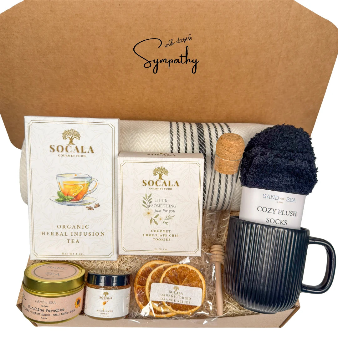Sympathy gift box with blanket, tea, honey, and other items on a white background.