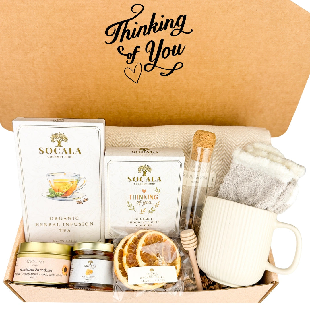 Gift box with blanket, tea, cookies, and other items labeled 'Thinking of You' with a heart symbol.